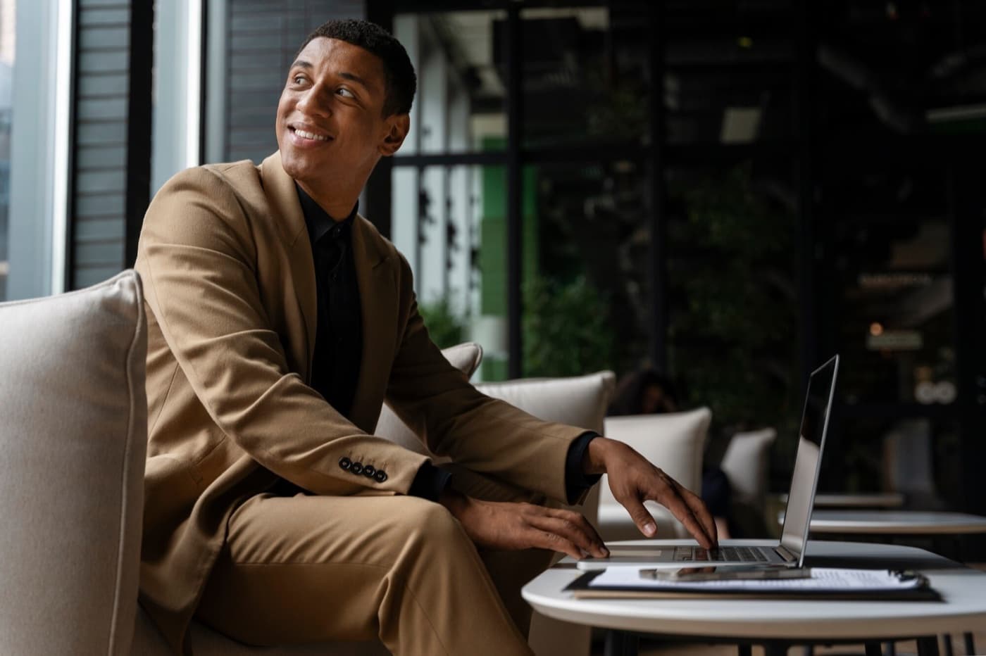 Smiling investor in a tan blazer working on a laptop